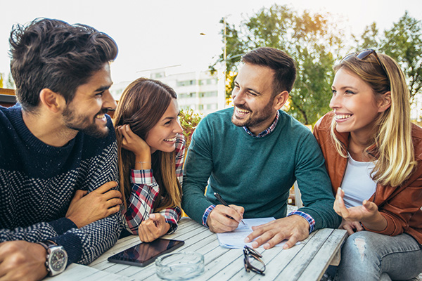 Group of four friends having fun a coffee together. Two women an Group of four friends having fun a coffee together. Two women and two men at cafe talking laughing and enjoying their time